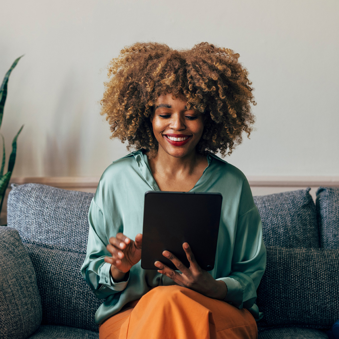 woman in a teal shirt reading from tablet and smiling